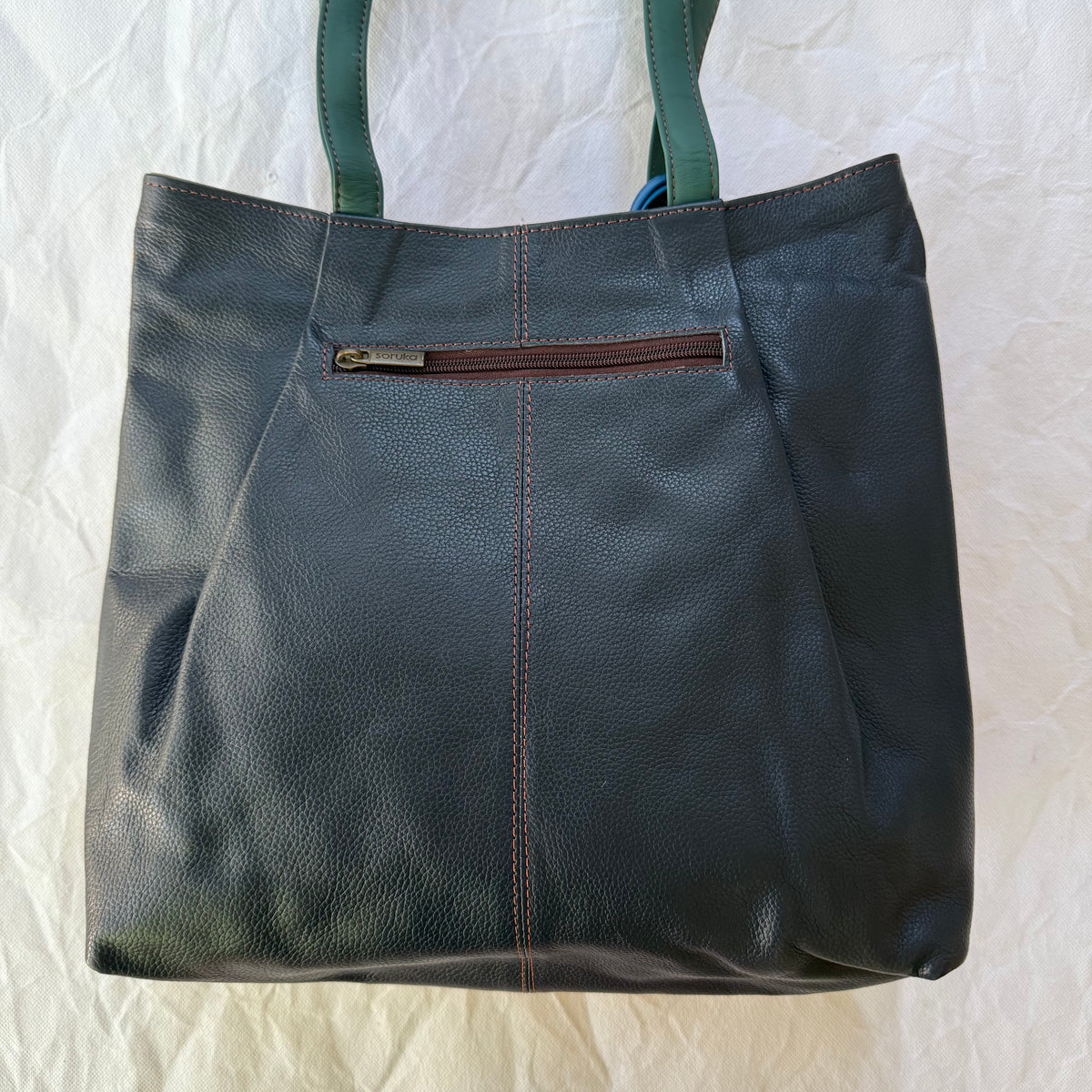 back view of tote with deep navy leather and zippered pocket