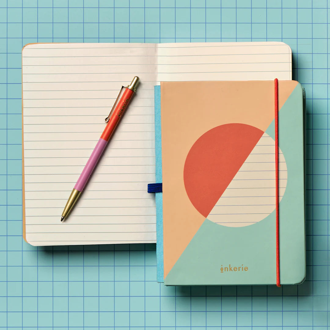 lined notebook laying open with a pen on it on a blue grid surface