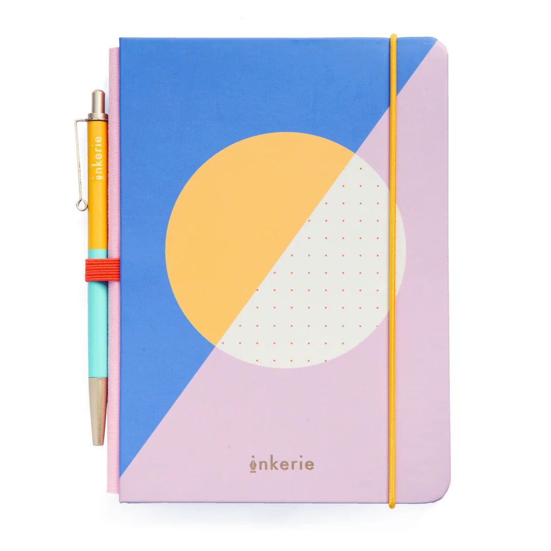 small note book with blue, pink, and yellow cover and yellow and turquoise pen in a loop on its spine