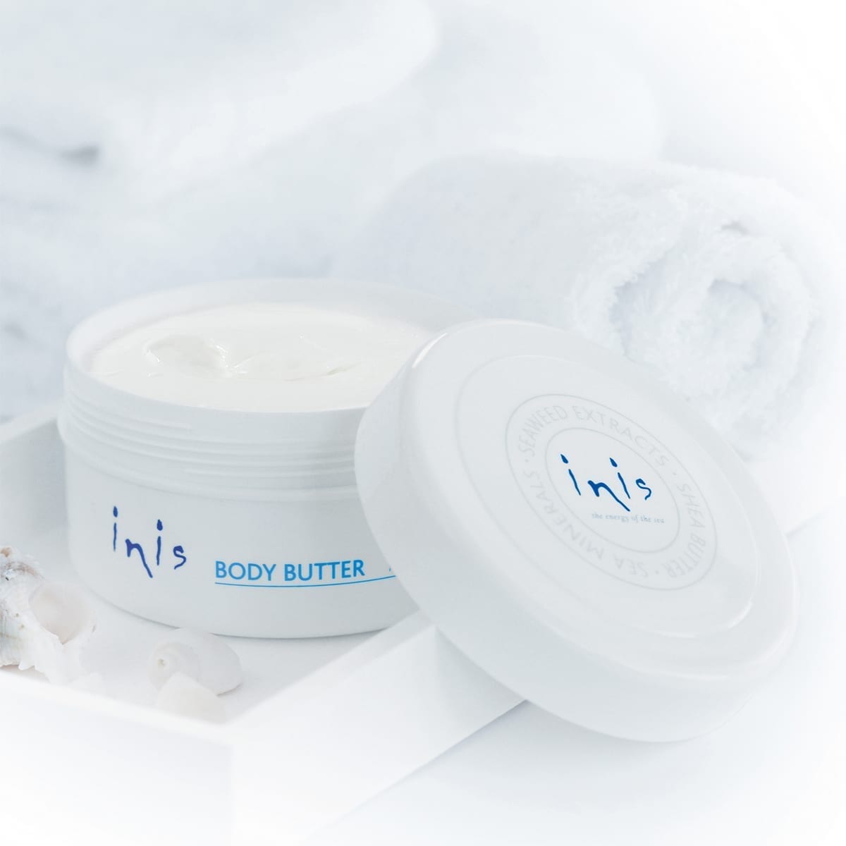 open jar of inis body butter set on a bathroom counter.