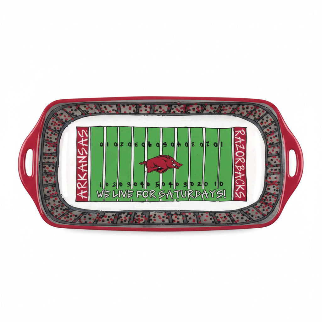 A rectangular serving platter with handles, featuring a football field design. The center is green with white yard lines, a red Arkansas Razorbacks logo, and the text 'WE LIVE FOR SATURDAYS!'.