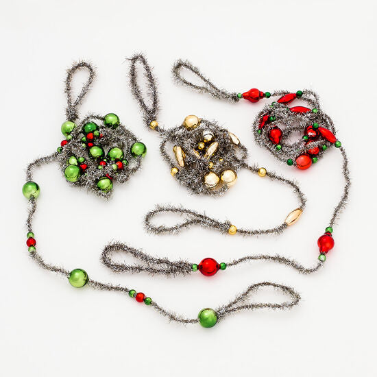 3 colors of tinsel and glass garlands arranged on a white surface
