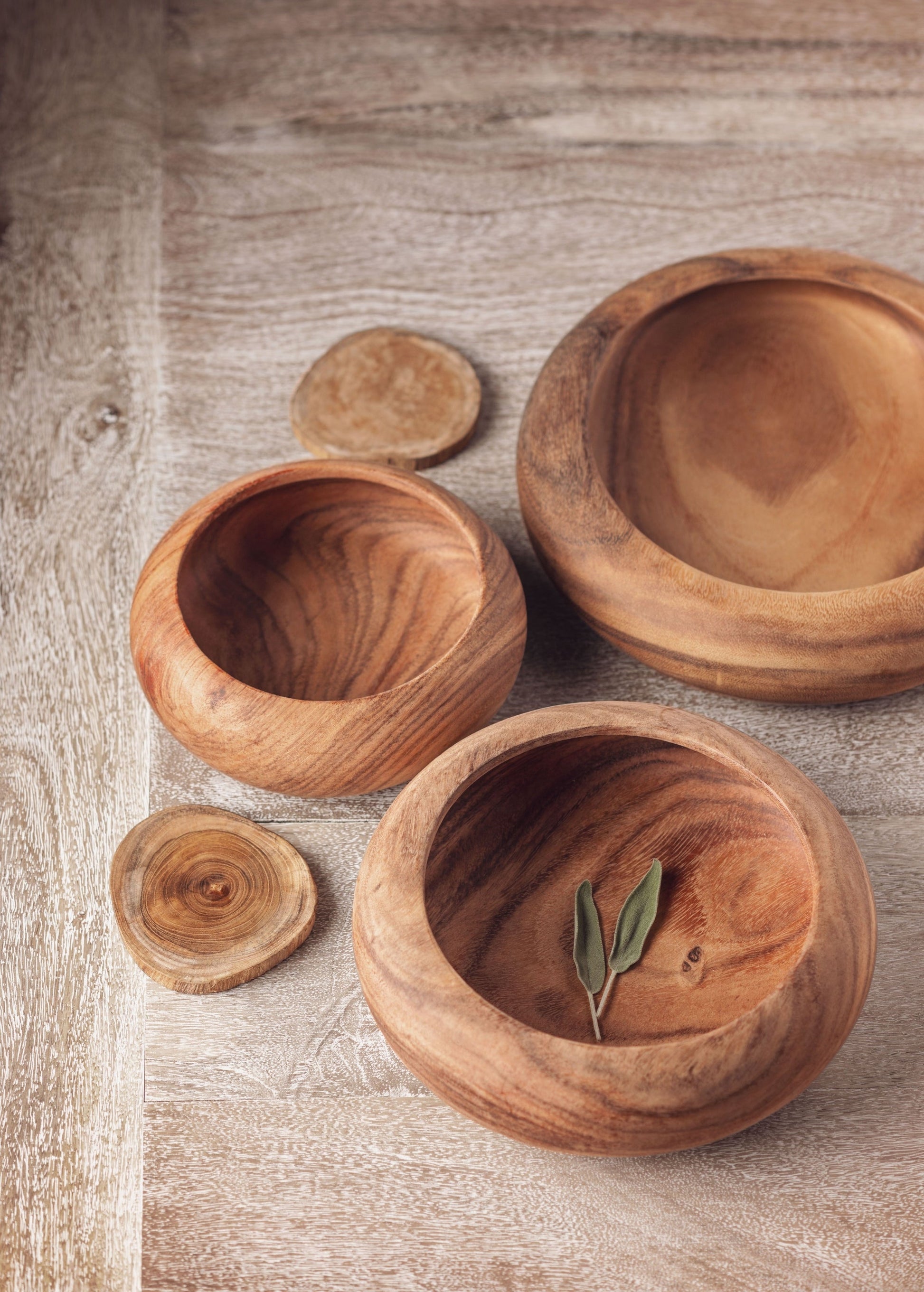 assorted sizes of round wooden bowls on a light wooden table.