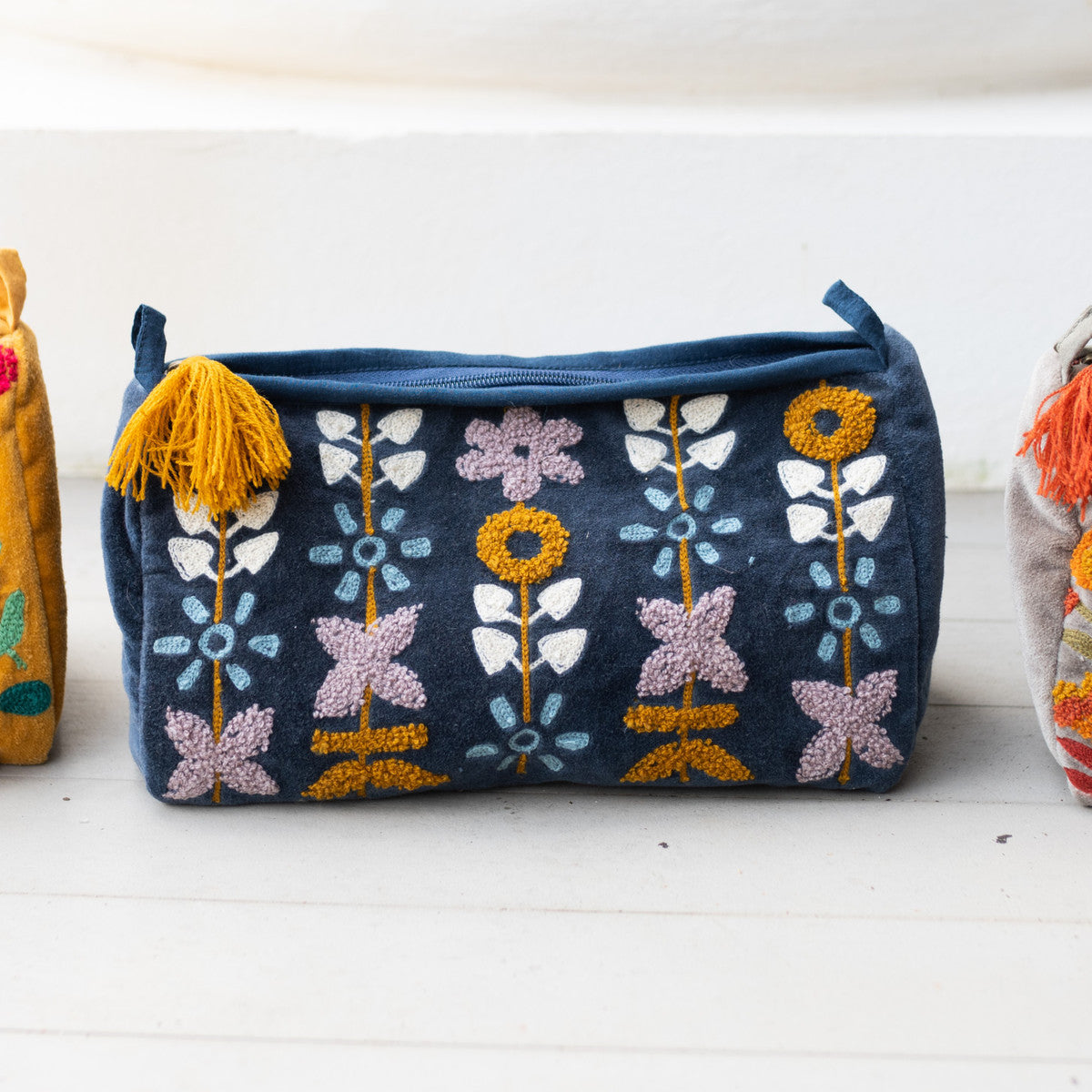 blue zipper bag with floral embroidery on a white counter.
