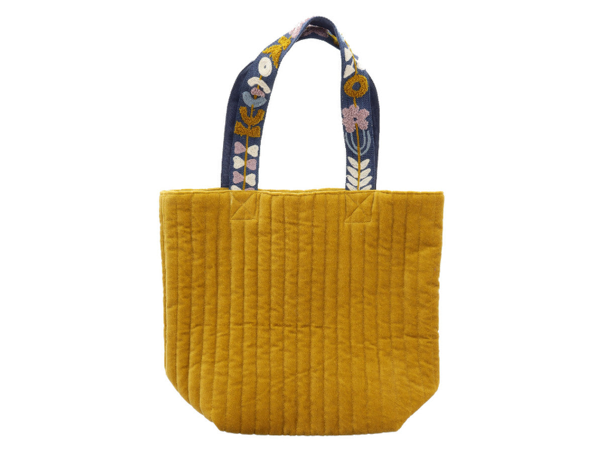 mustard colored velvet tote with blue floral handles on a white background.