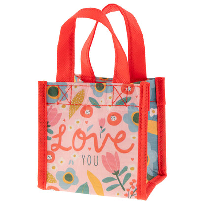 small pale pink gift sack with red handles and trim and colorful floral design and "love you" printed on it