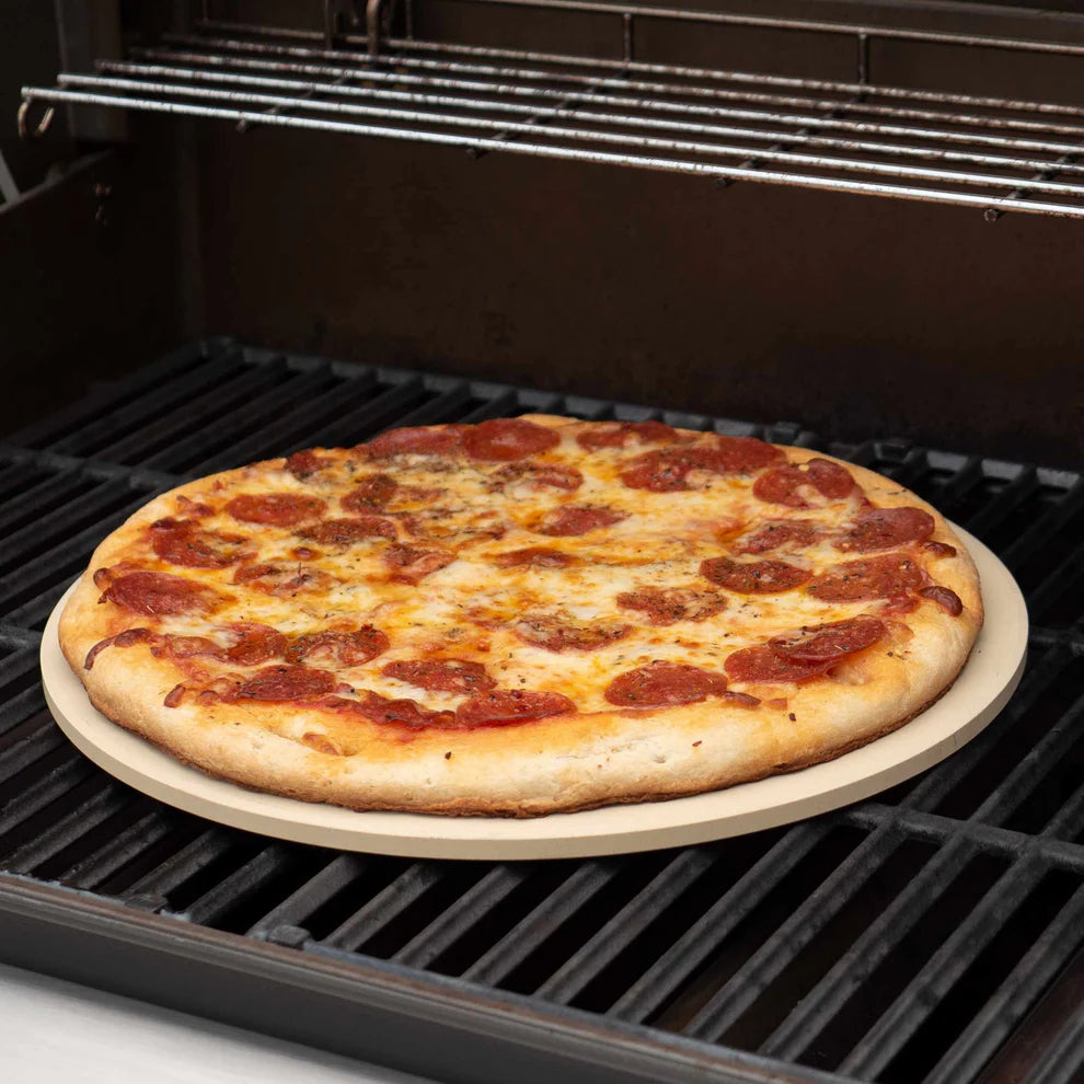 round baking stone in an oven with a pizza on it
