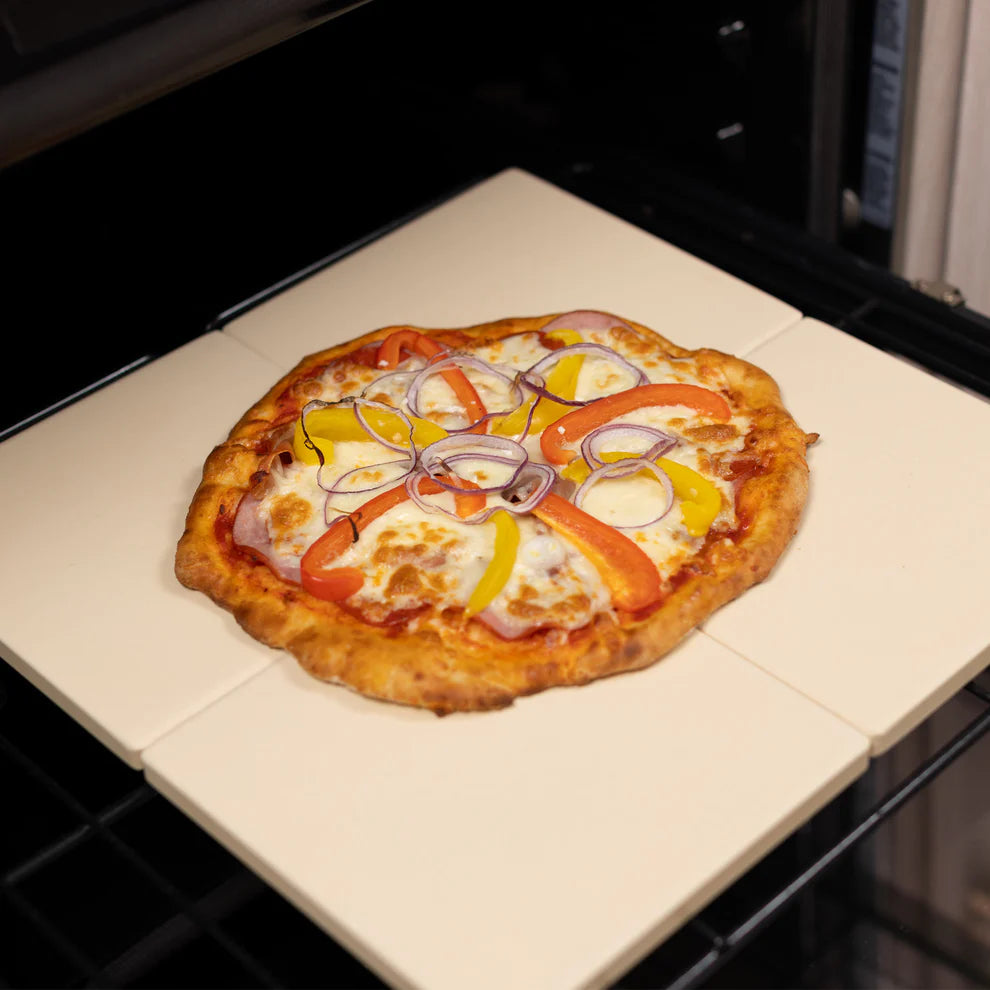 4 pizza stones in a oven with a large pizza across them