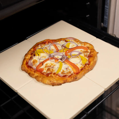 4 pizza stones in a oven with a large pizza across them