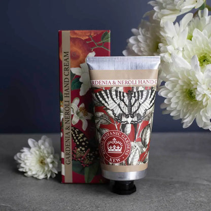 Hand cream with butterfly and floral packaging and white flowers on a dark background