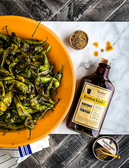 bottle Kentuckyaki laying on a table with grill peppers and spices.