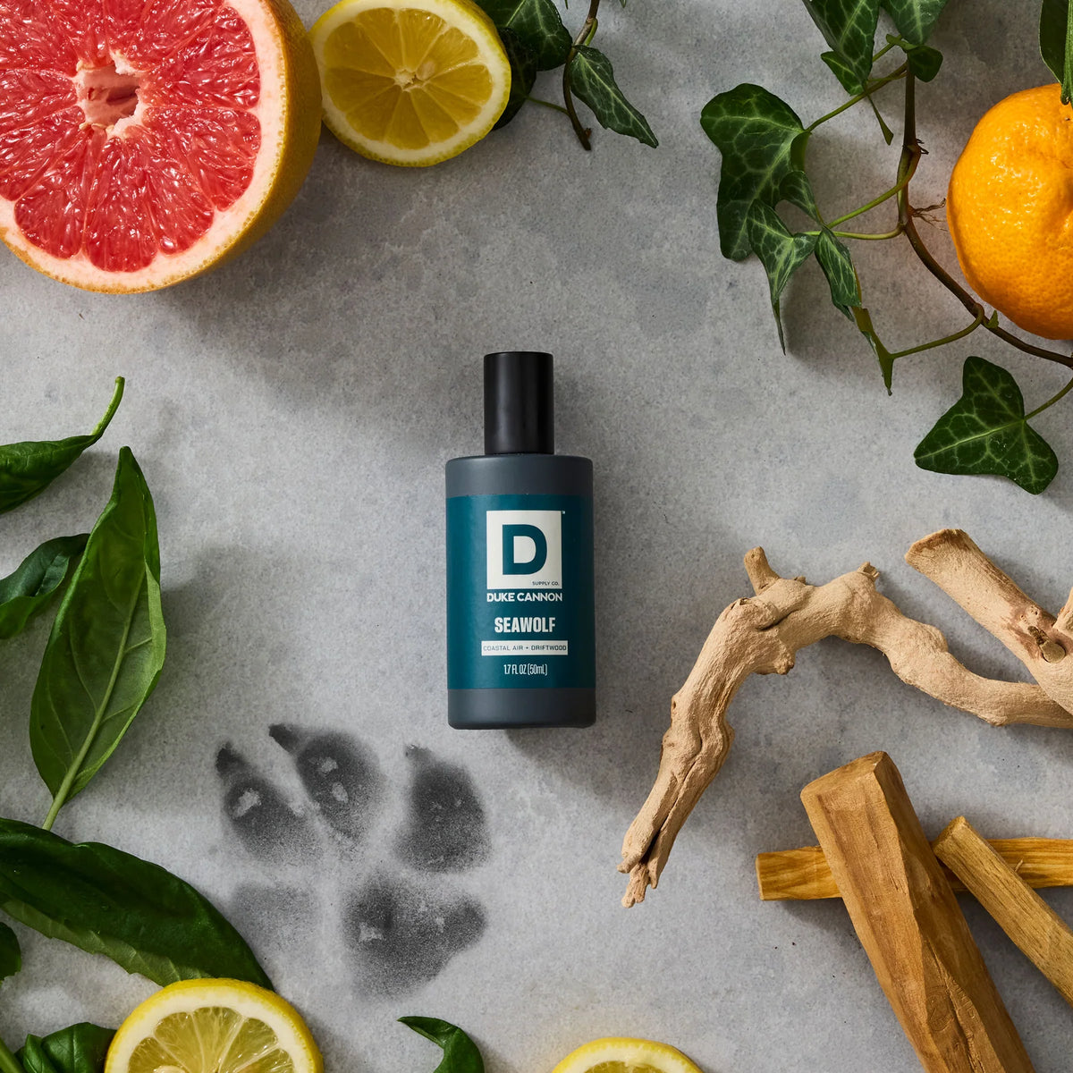 Seawolf Proper Cologne bottle on a stone background surrounded by wood, citrus, and a wolf paw print
