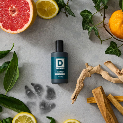 Seawolf Proper Cologne bottle on a stone background surrounded by wood, citrus, and a wolf paw print