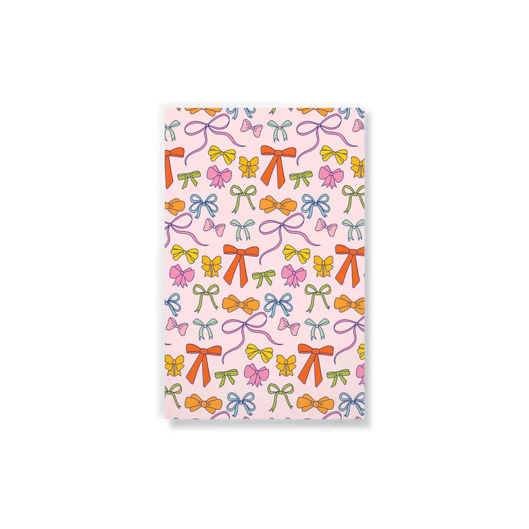 light pink notebook printed with colorful bows.