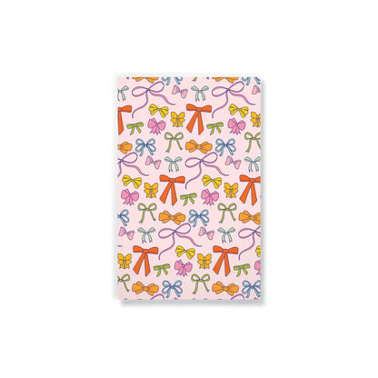 light pink notebook printed with colorful bows.