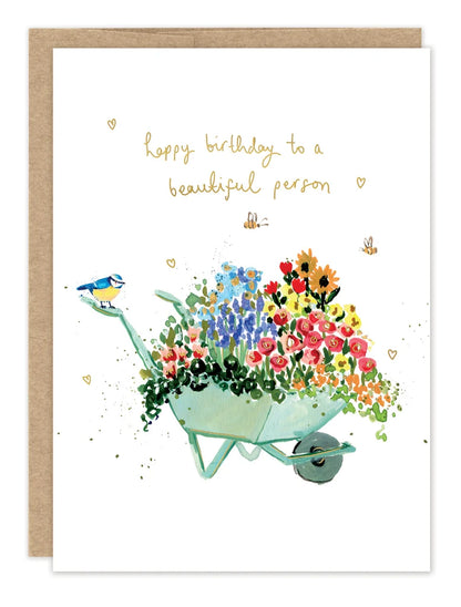 front of card featuring a wheelbarrow of flowers and gold text