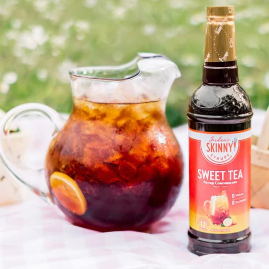 bottle of sweet tea concentrate skinny syrup set next to a pitcher of sweet tea.