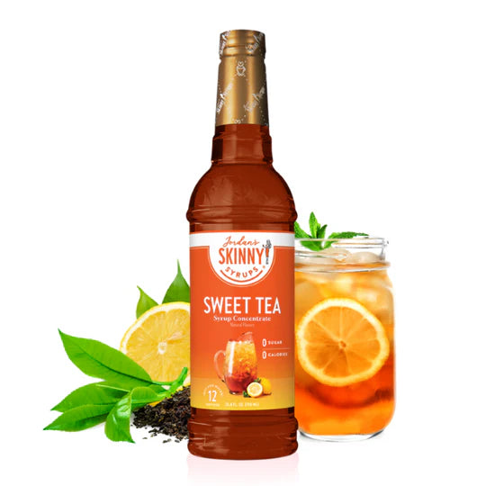 bottle of sweet tea concentrate skinny syrup set next to a glass of sweet tea, lemons, and tea leaves.