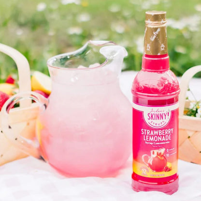 bottle of Strawberry Lemonade skinny syrup set next to a pitcher of pink lemonade.