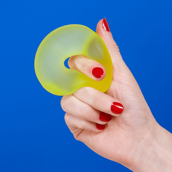 Hand holding a yellow stress ball loop against a blue background