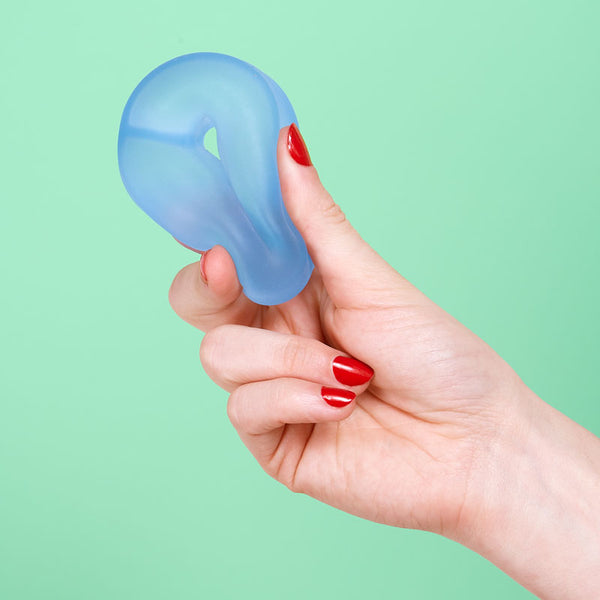 Hand holding a blue silicone stress ball against a green background