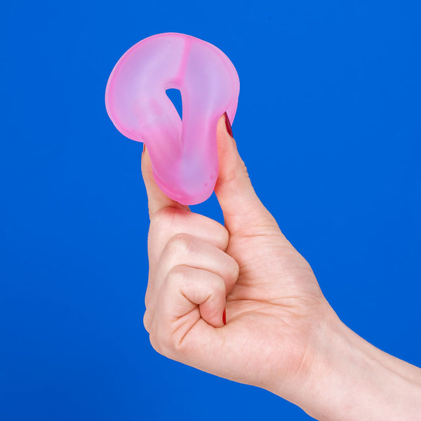 Hand holding a pink silicone ring against a blue background