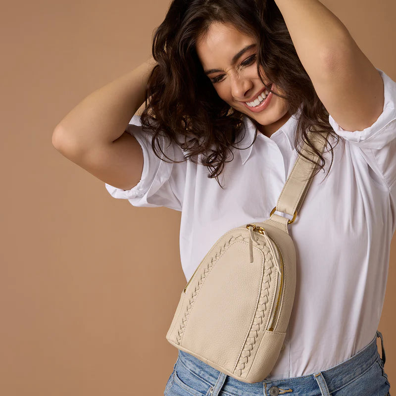 person wearing jeans and a white top with birch fern sling bag across their chest