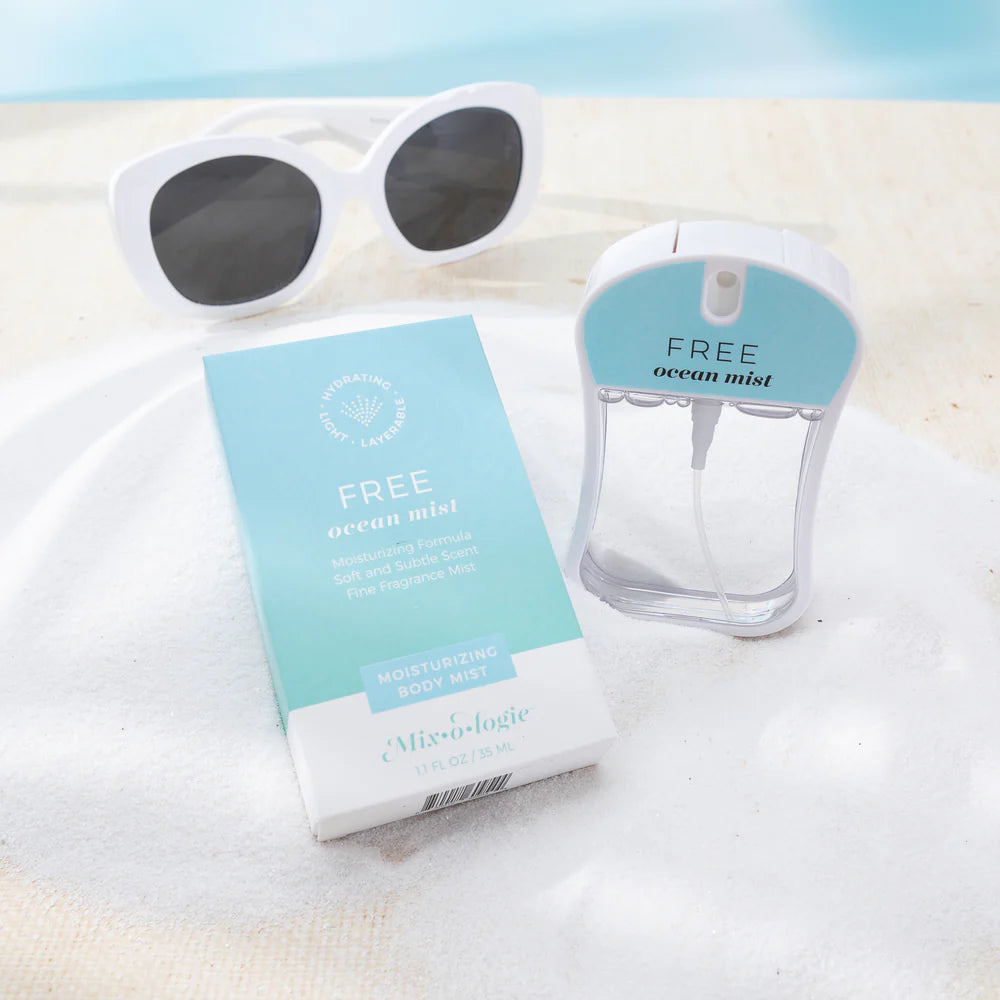 free ocean mist body spray styled on a white towel with white sunglasses in the background.