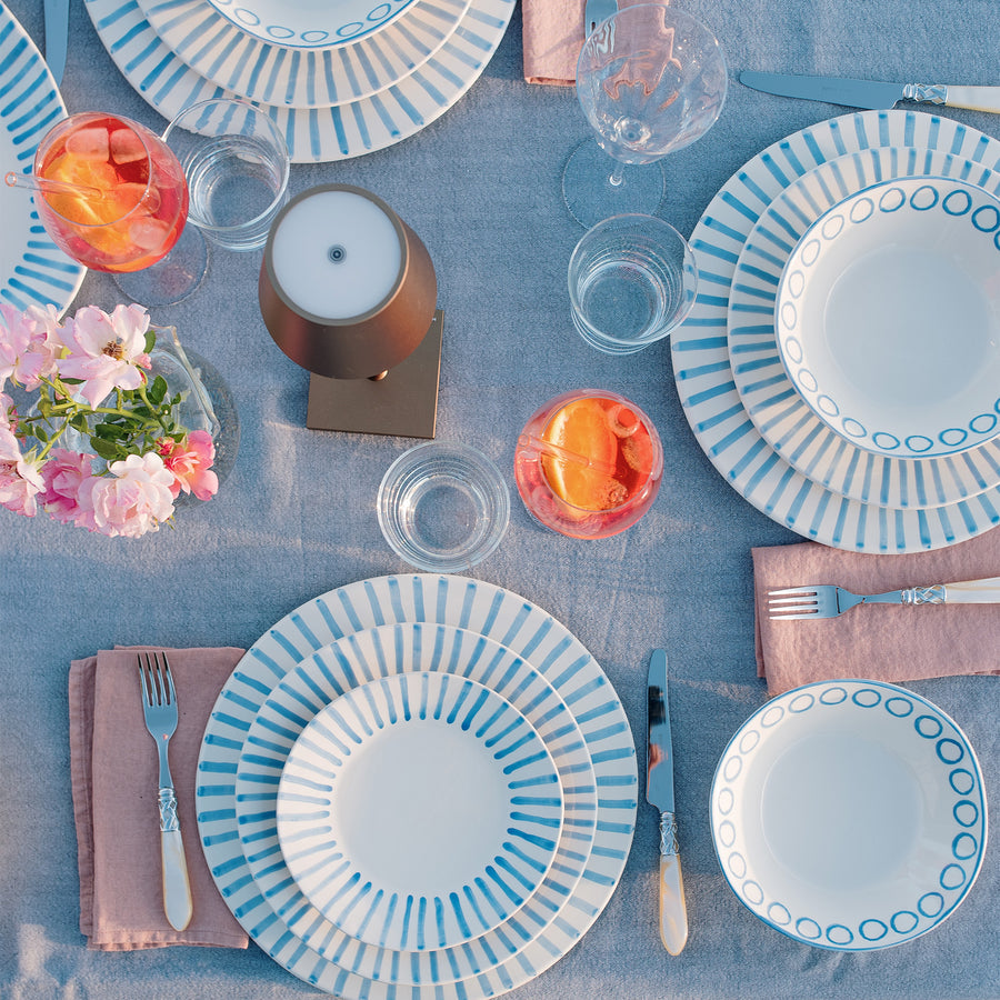 top view of a table set with modello dinner ware, glasses, linens, and silverware.