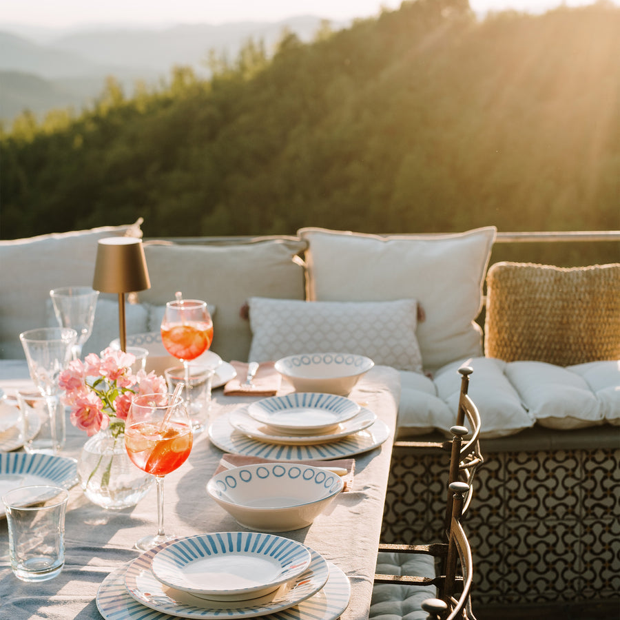 table set with modello place settings, glasses, and linens with a mountain view background.