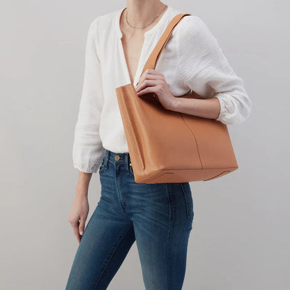 person wearing jeans and a white top with the biscuit vida tote on their shoulder.