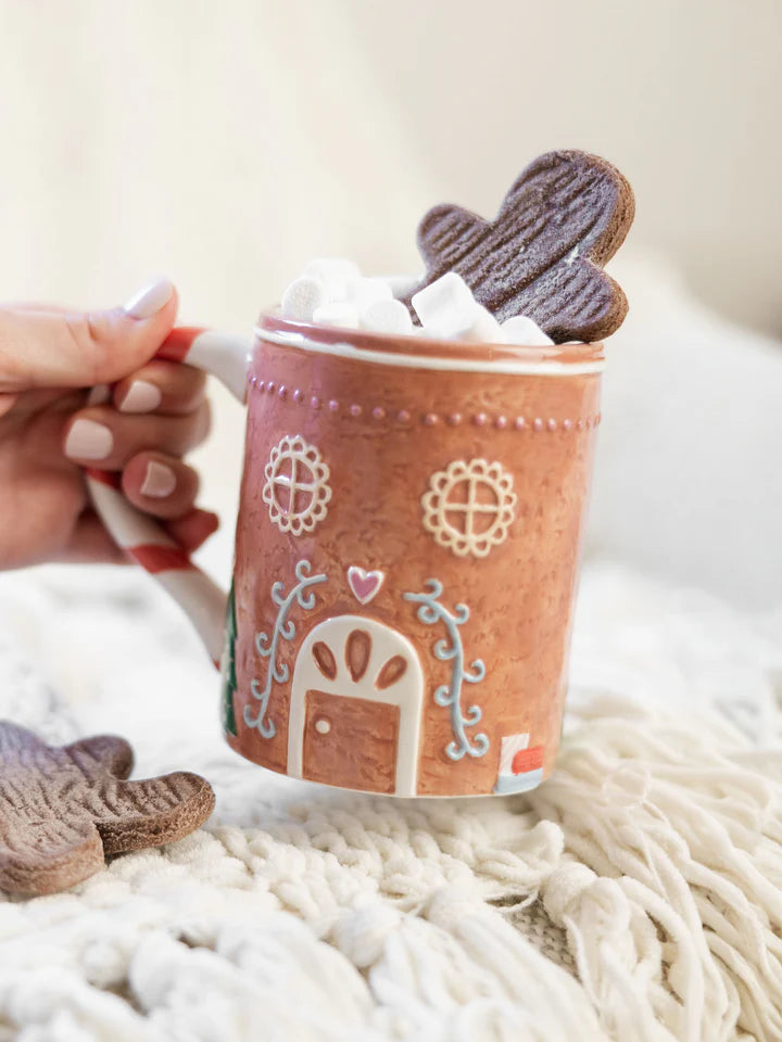 Hand holding gingerbread house mug.