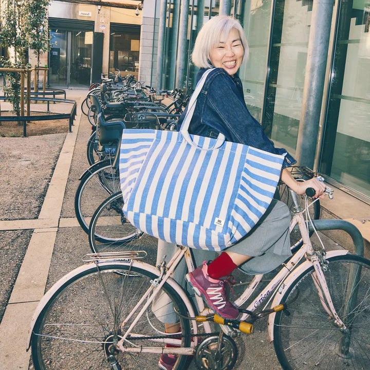 Person with a blue and white striped bag on a bicycle in an urban setting