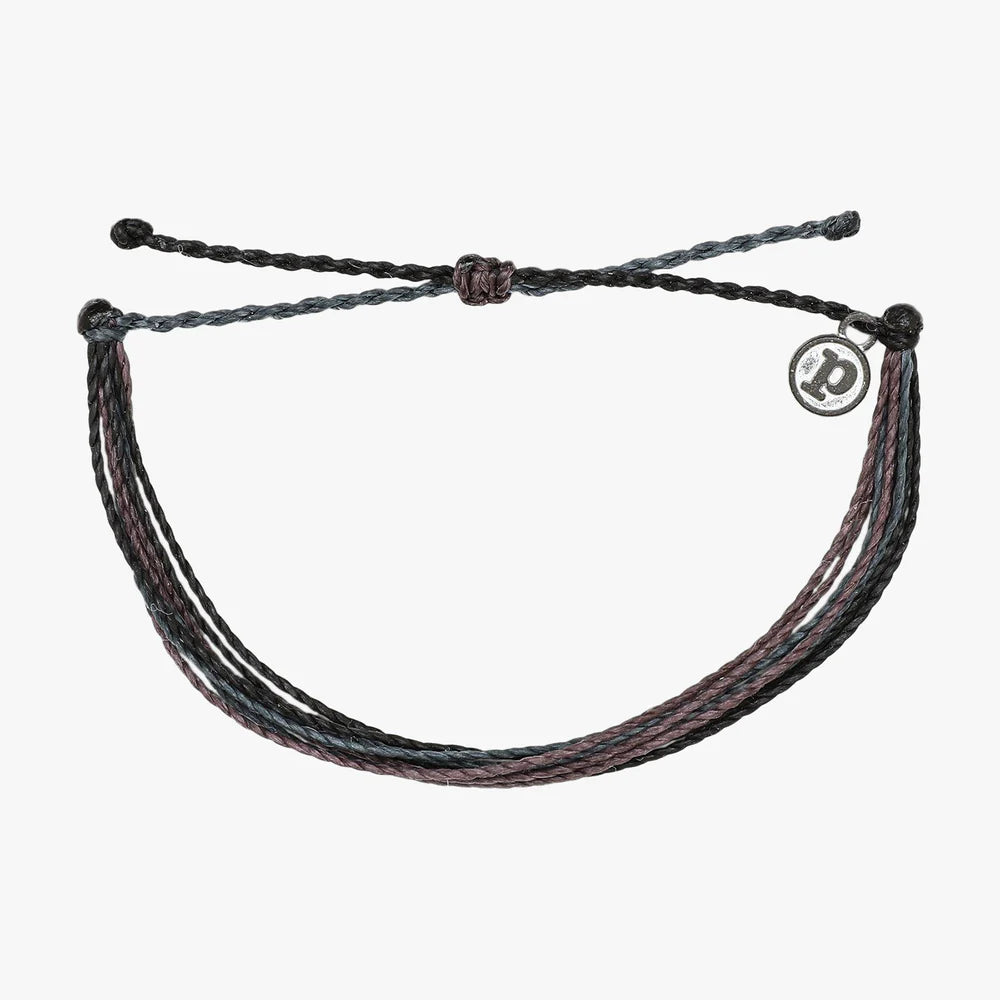 Pura Vida multi strand corded bracelet in varying shades of dark blue, purple, and black with a Pura Vida logo charm