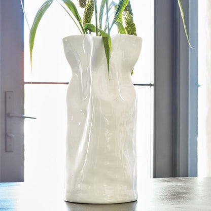 large cinched vase filled with greenery set on a table