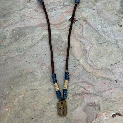 Aadi Guardian Cross Necklace laying on a rock slab