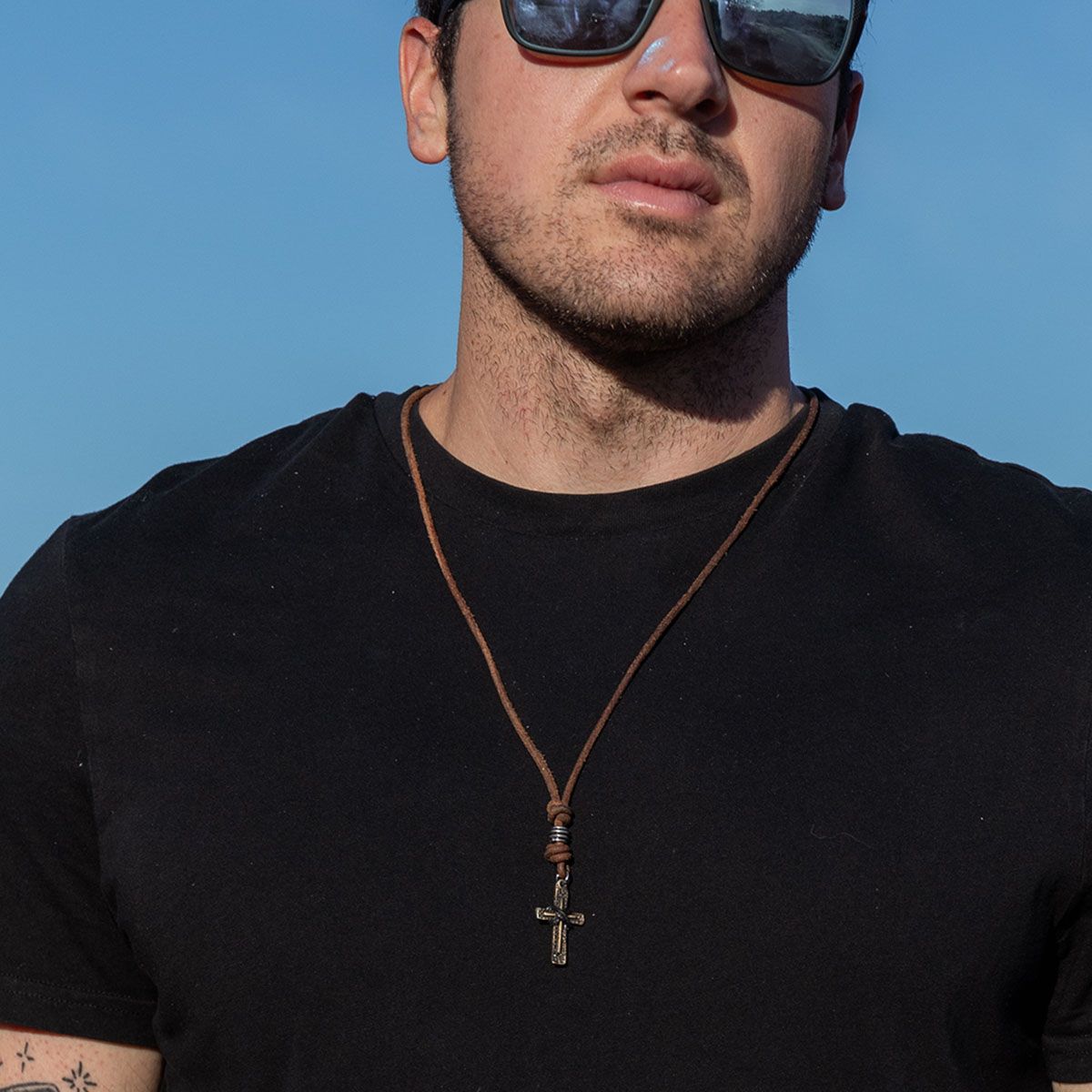 person wearing black t shirt and Aadi Cross Leather Necklace