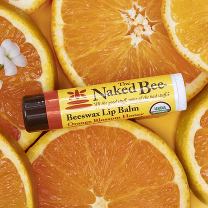 Naked Bee lip balm on sliced oranges with visible USDA Organic label