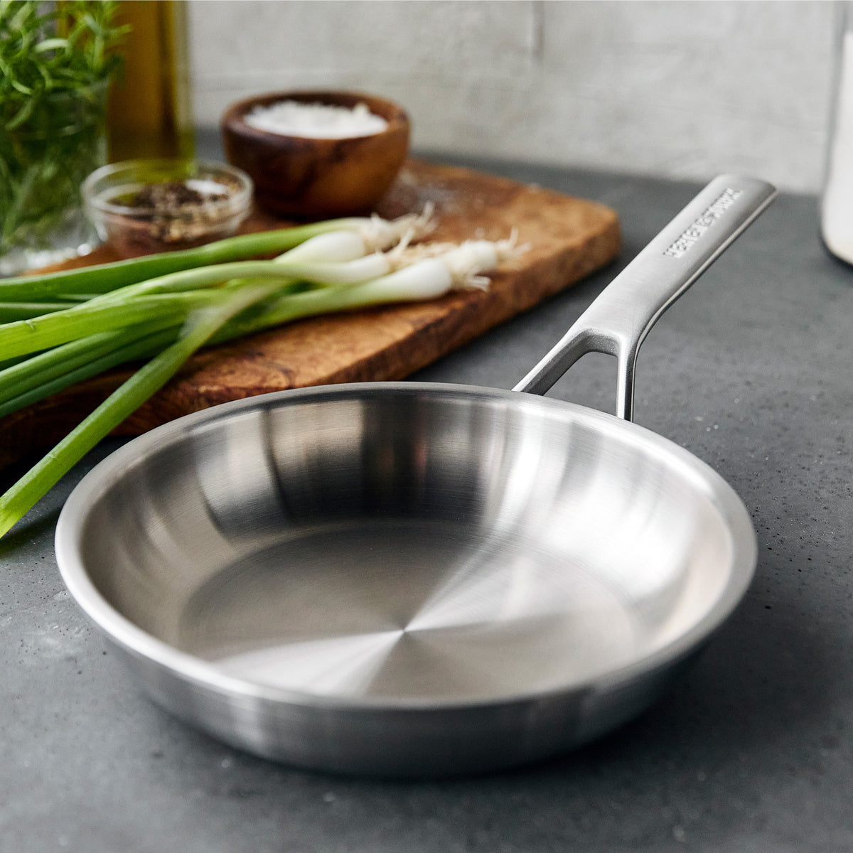 8 inch frypan set on a stone counter with a cutting board, green onions and spices behind it.
