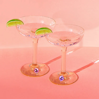 2 margarite glasses with lime wedges on the rims and disco ball drink markers on the stems.