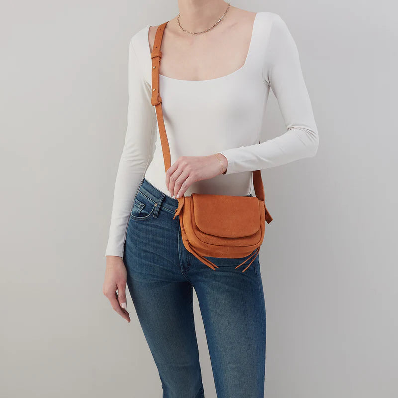 person wearing jeans and a white top with marmalade bonita bag across their chest.