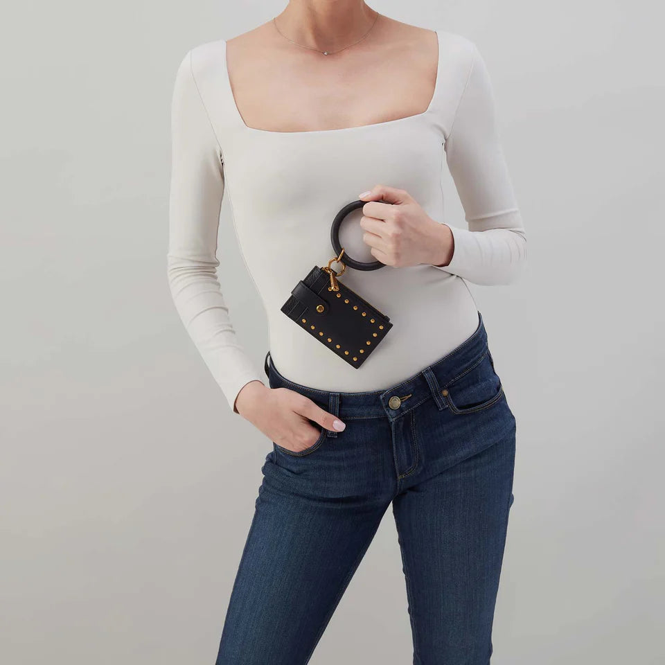 person wearing jeans and a white top holding black studded Ring Credit Card Wristlet