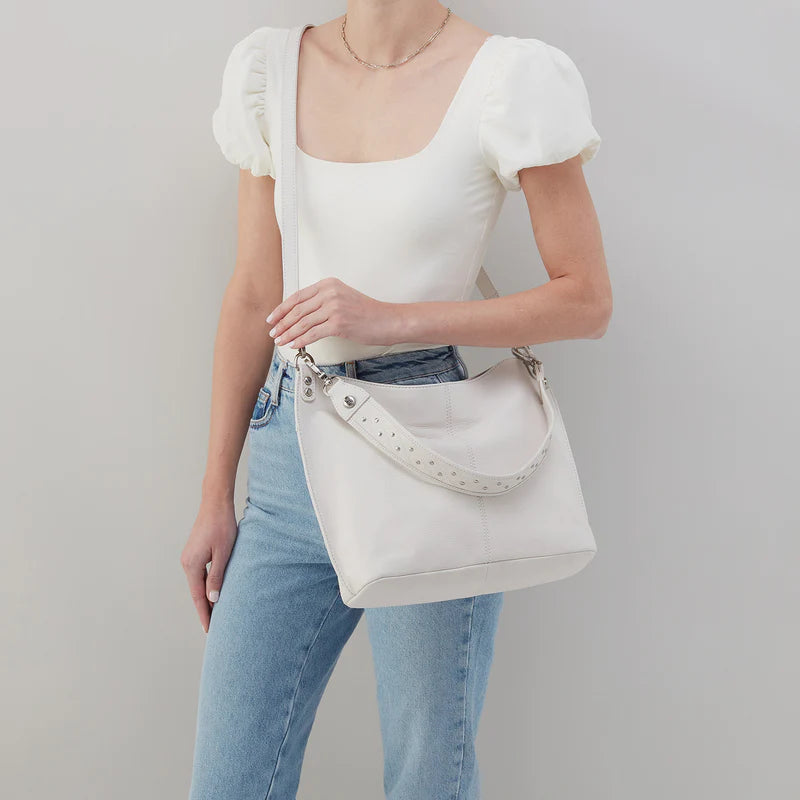 person wearing jeans and a white top with white pier bag across the chest.