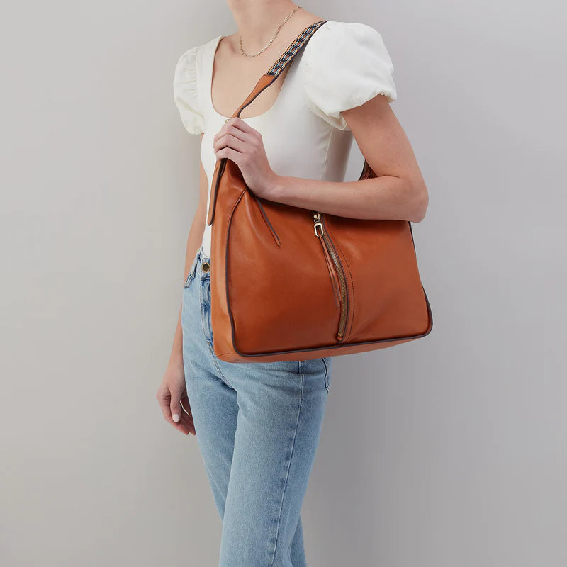 person wearing jeans and a white top with honey brown bellamy bag on their shoulder.