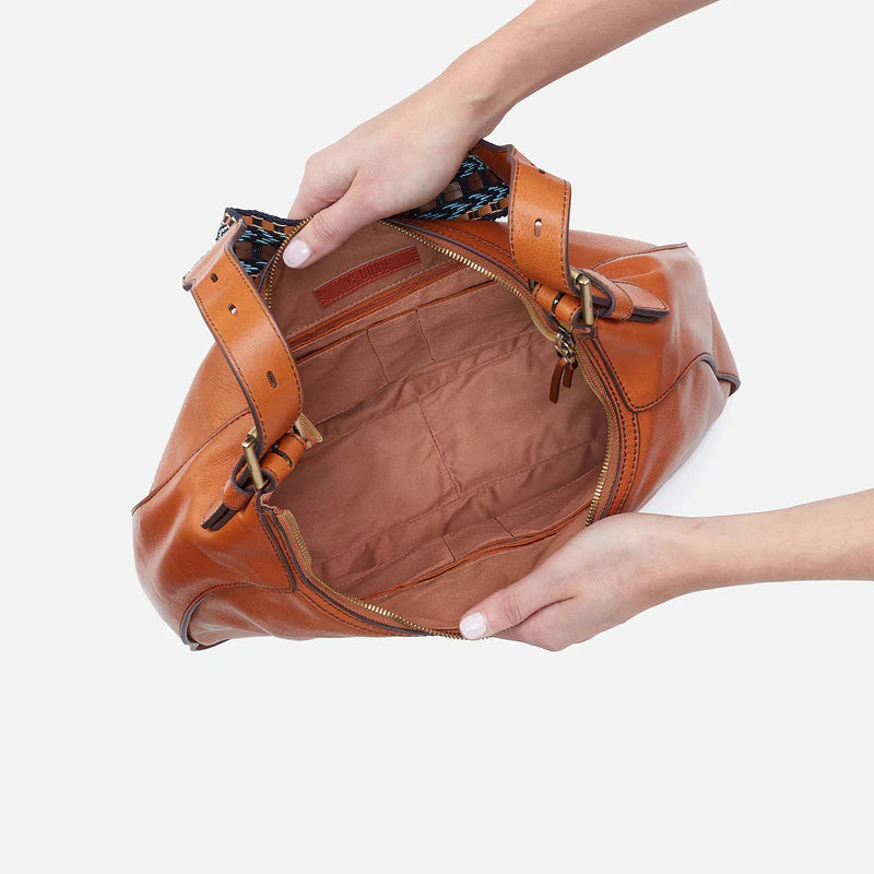 hands holding open honey brown bellamy bag showing interior.