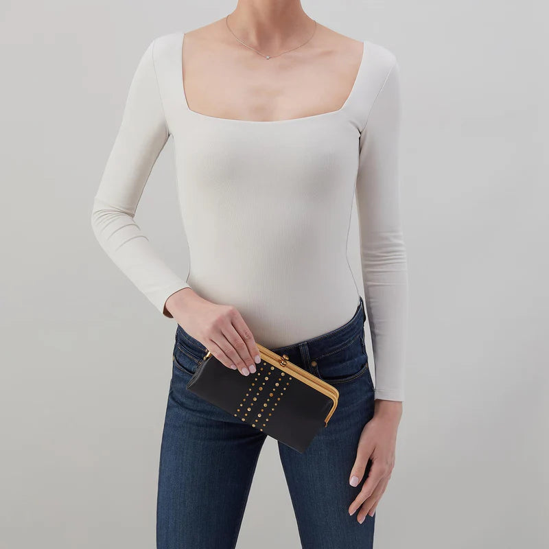 person wearing jeans and a white top holding Lauren Clutch Wallet in black with gold studs