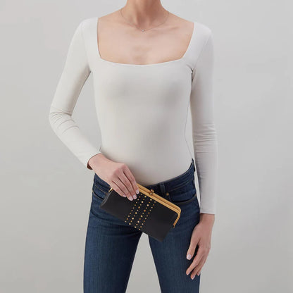 person wearing jeans and a white top holding Lauren Clutch Wallet in black with gold studs