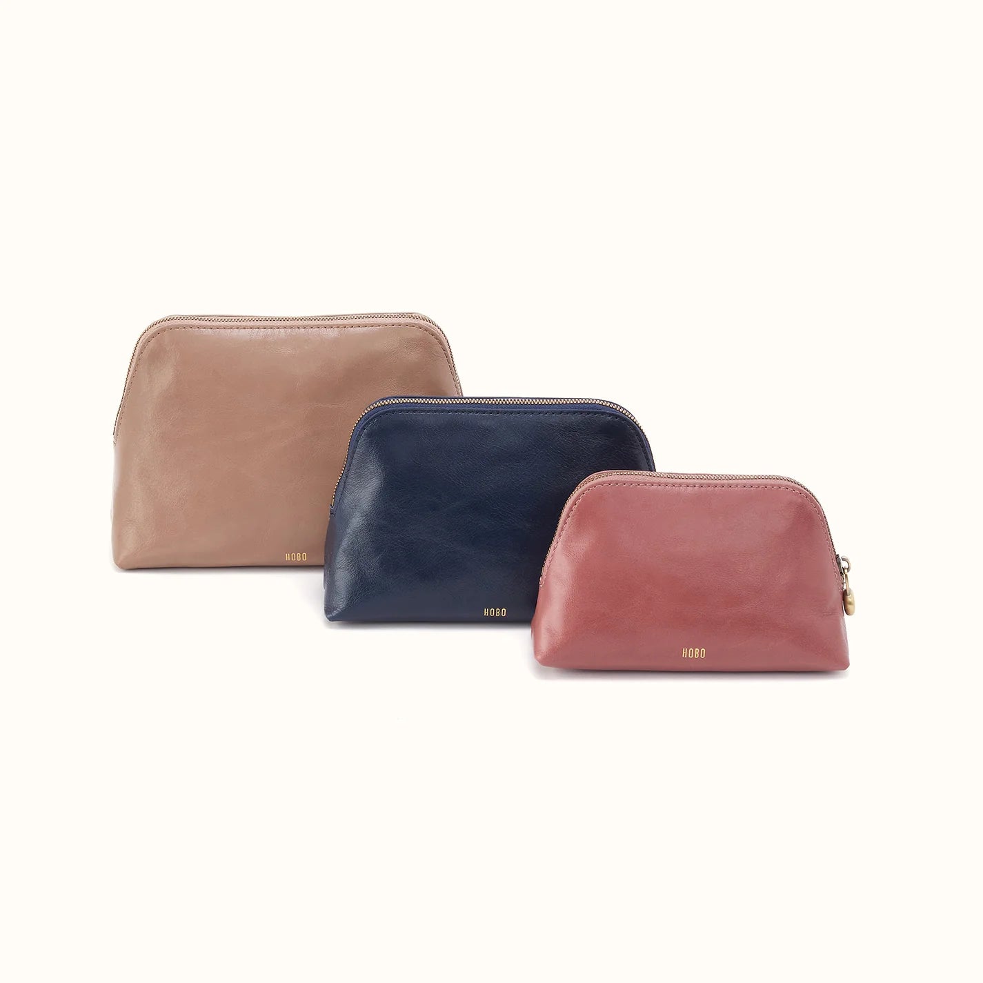 tan pouch behind a navy pouch behind a rose color pouch
