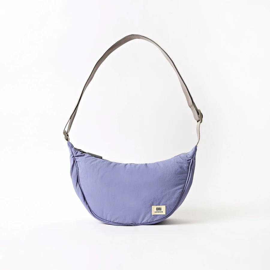 lavender shoulder bag with crescent shape and grey strap shown on a white background