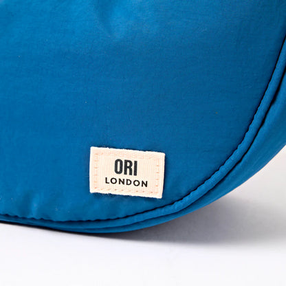 close-up of botton corner of Blue bag with an 'ORI London' label on a white background
